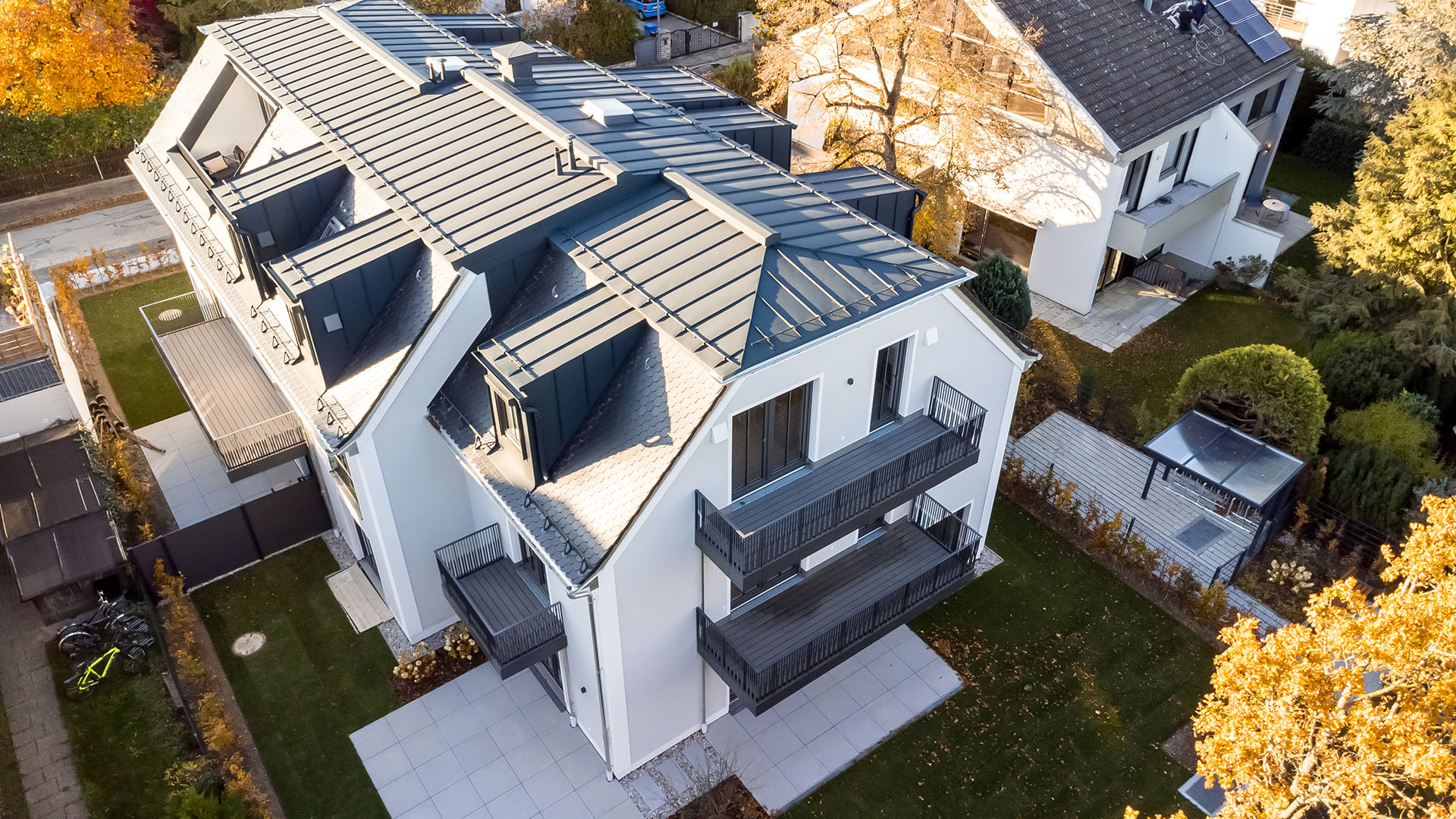Luftbild eines Mehrfamilienhauses mit fünf Wohnungen und Tiefgarage mit Mansard-Walmdach von DOMINO Bau in der Thaddäus-Eck-Straße in München-Obermenzing