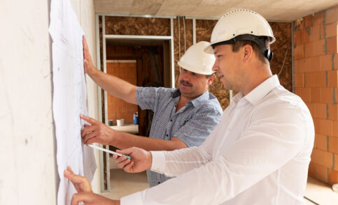 2 construction managers with helmets on the construction site of a shell building