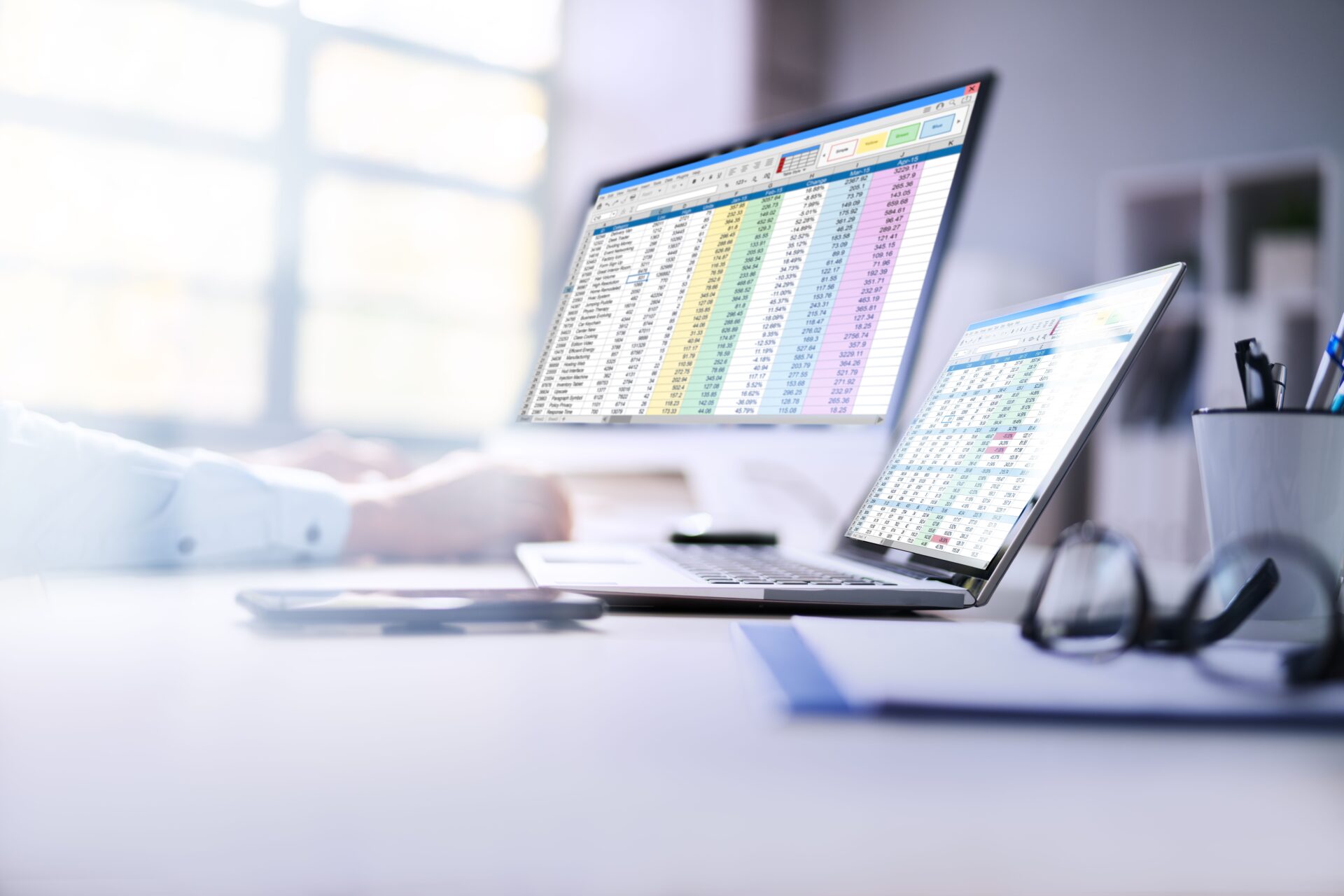 Zwei Monitore mit Excel-Dateien und Zahlen, Renditeberechnungen