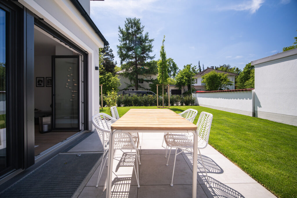 Terrace and garden with a view into the living room; new semi-detached house by DOMINO Bau in Munich Obermenzing