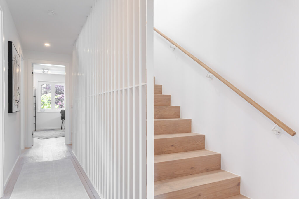 Staircase in the house with wooden stairs; new semi-detached house by DOMINO Bau in Munich Obermenzing