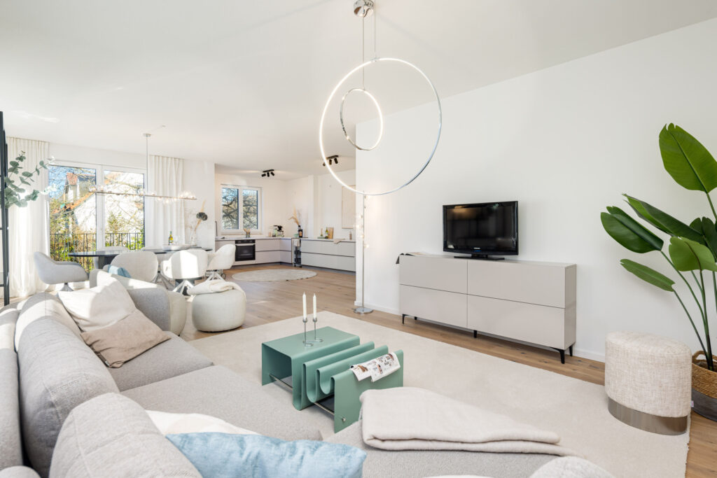 Image of a living room with dining table, sofa area, and kitchen on the upper floor of a ready-to-move-in new apartment in Trudering by Domino Bau