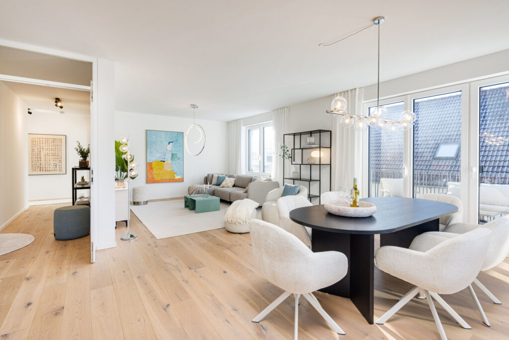 Image of a living room with dining table and sofa area, looking towards the hallway on the upper floor of a ready-to-move-in new-build apartment in Trudering by Domino Bau.